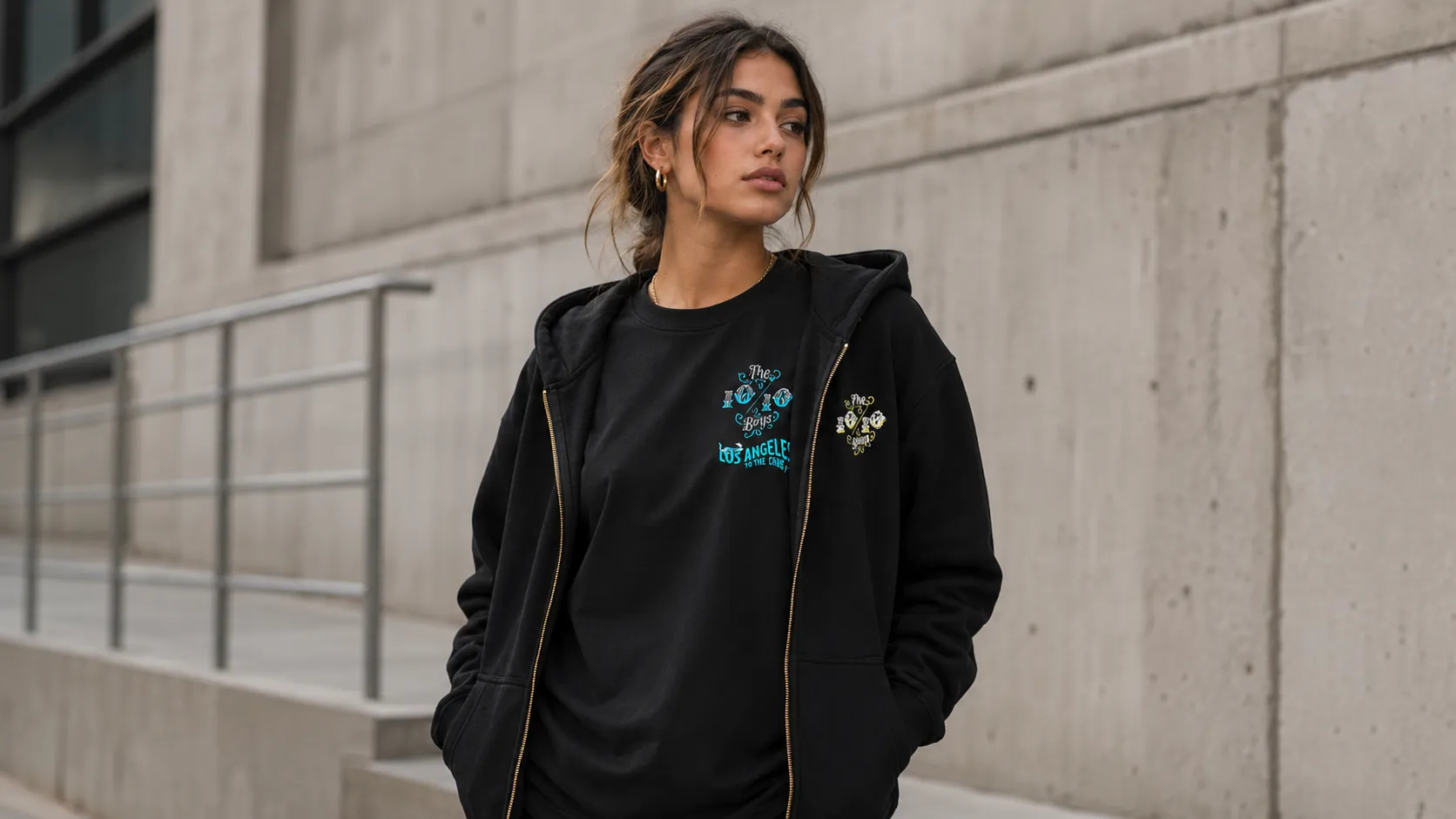 Clean layered streetwear with a black premium hoodie worn over a tee showing balanced proportions against concrete