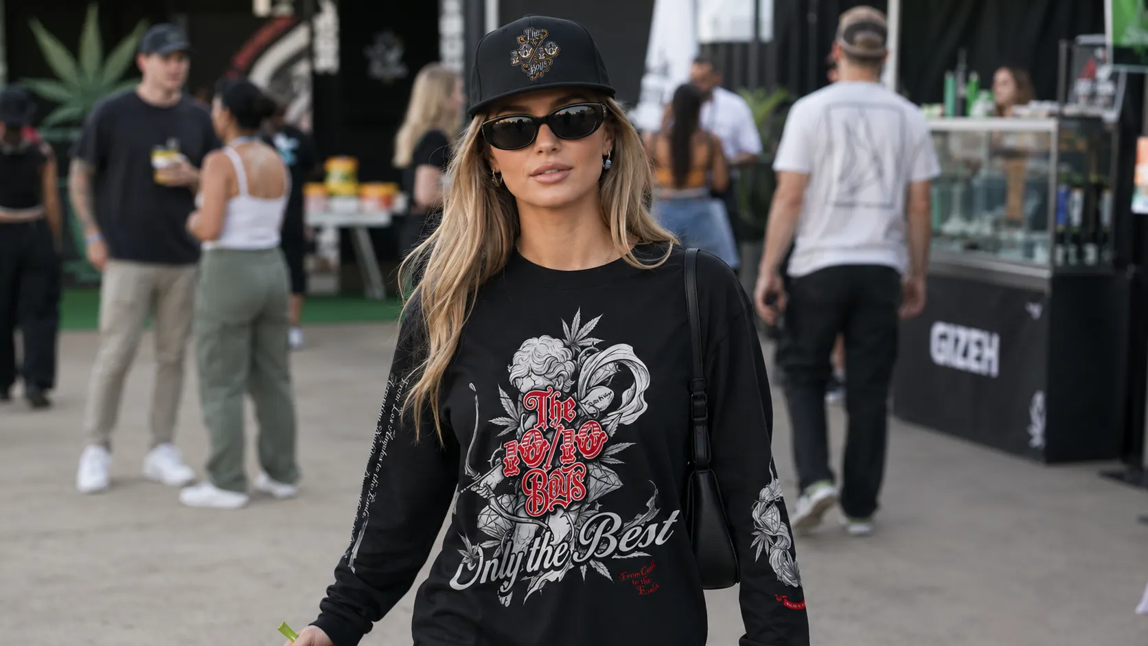 Festival-goer in a black The 10/10 Boys long-sleeve streetwear top, cap and sunglasses walking through a cannabis festival