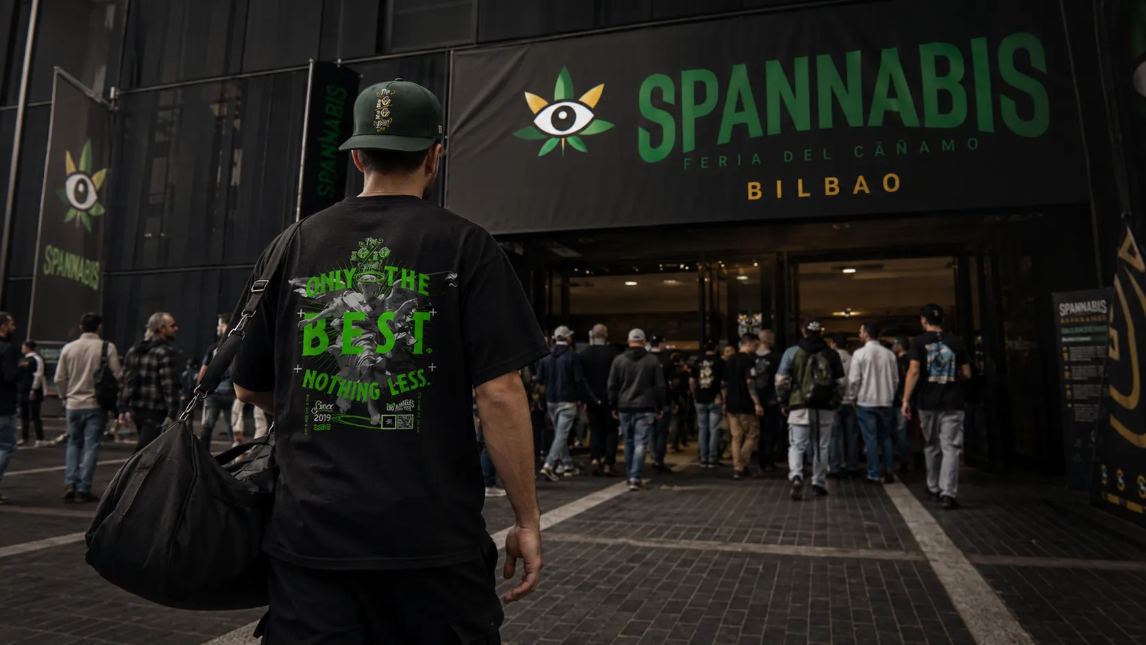 Cap and tee streetwear travel outfit with duffel bag outside Spannabis Bilbao