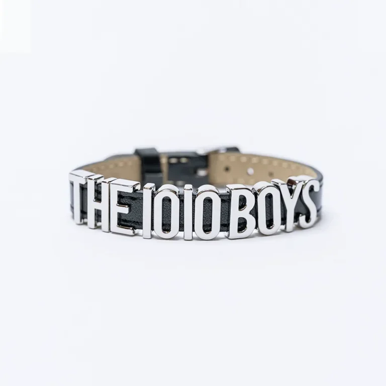 The 10/10 Boys bracelet — black leather with a polished THE 10/10 BOYS metal nameplate