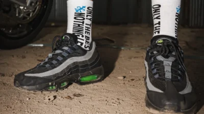 Close-up of the 10/10 Boys crew socks worn with black trainers, showing the cuff lettering and fleur-de-lis detail