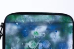 Close-up of the Big Laptop Bag: Only the Best × ArtLife lettering and splatter over blue and green