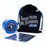 The 10/10 Boys 7th Anniversary Grinder in blue and black with its Seven Years. One Standard. drawstring pouch and sticker sheet